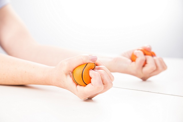 A person doing mirror box therapy with their hand squeezing a ball.